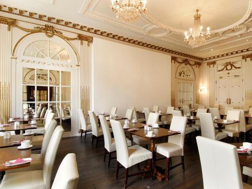 a dining room with tables and chairs and a chandelier at Grand Royale Hyde Park in London