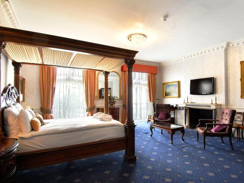 a bedroom with a canopy bed and a television at Grand Royale Hyde Park in London