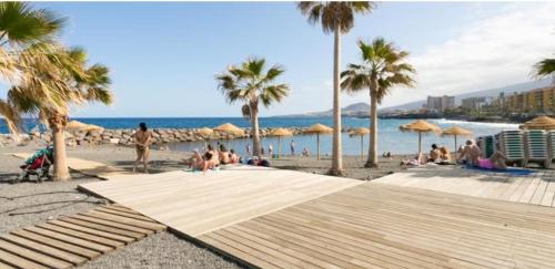 a group of people sitting on a beach with palm trees at THE POPPIES Guest House - 100m Ocean - Private Spaces in Candelaria