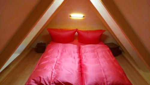 a red bed with two red pillows in a attic at Mini Beach House I Sylt/Rantum in Rantum