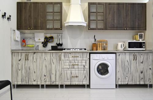 a kitchen with wooden cabinets and a washing machine at Апартаменты Park & House 42 на 5 гостей рядом с Источником и парком in Essentuki