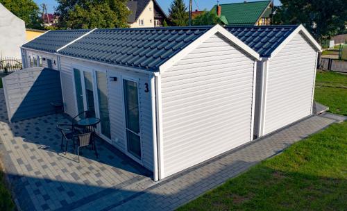 a white shed with a blue roof on a patio at Maximus domki in Krynica Morska