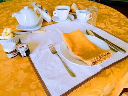 a table with a yellow table cloth with a plate and utensils at Locanda del Boscogrande in Montegrosso dʼAsti
