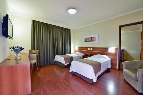 a hotel room with two beds and a table at Curi Palace Hotel in Pelotas