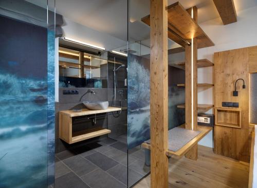 ein Bad mit einem Waschbecken und einer Glasdusche in der Unterkunft Apartments Riega in Sexten