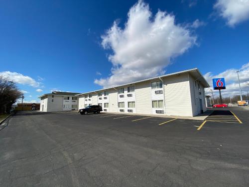 a large white building with a car parked in a parking lot at Motel 6-Fort Wayne, IN in Fort Wayne
