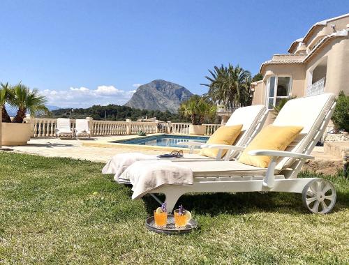 a white lounge chair sitting in the grass next to a pool at Jávea Apartment Mar in Jávea