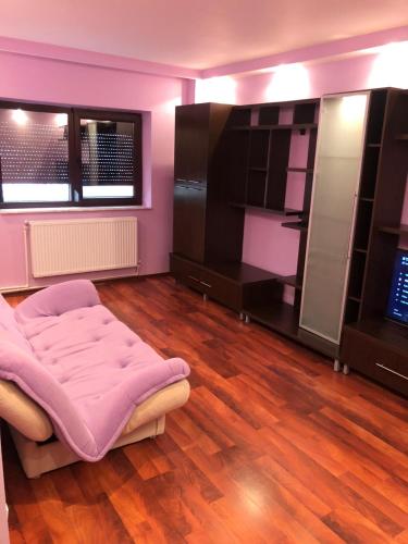 Habitación rosa con cama y suelo de madera. en Clau Apartment, en Galaţi