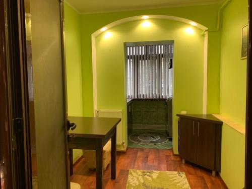 a room with green walls and a table and a window at Clau Apartment in Galaţi