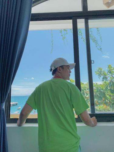 a man looking out of a window at the ocean at Sunbay Homestay Cu Lao Cham in Tân Hiệp