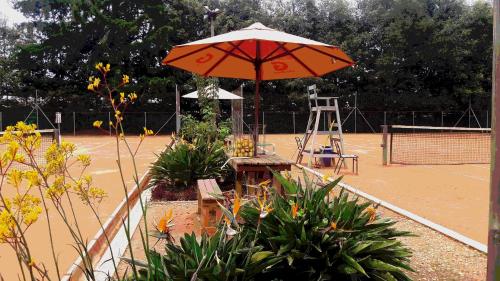 
a patio area with a table, chairs, and umbrella at Star Hostal - Club De Tenis in Rionegro
