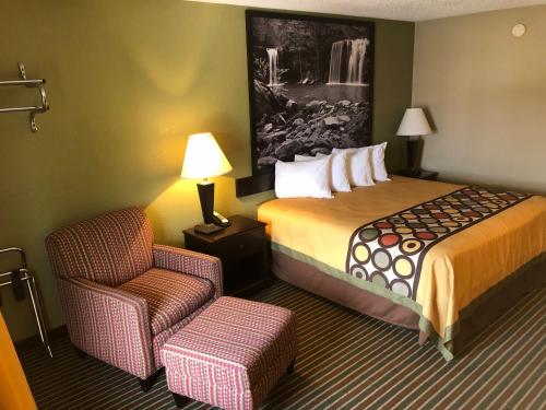 a hotel room with a bed and a chair at Super 8 by Wyndham Harrison AR in Harrison