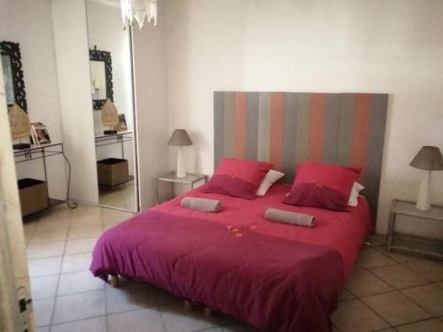 une chambre avec un grand lit avec des draps et des oreillers rouges dans l'établissement Mas Maurane - Le Romarin aux portes d'ARLES, à Tarascon