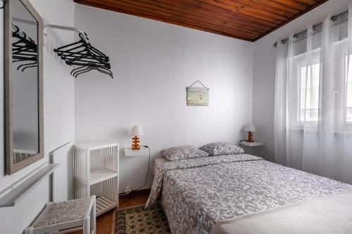um quarto branco com uma cama e uma janela em CASA DA FALÉSIA 28 - Casa em Peniche