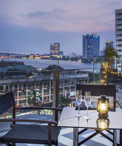 a table with two wine glasses on a balcony at Hotel Once Bangkok in Bangkok
