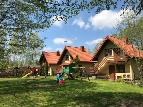 a house with a playground in the yard at Agroturystyka Źródełko in Święta Katarzyna