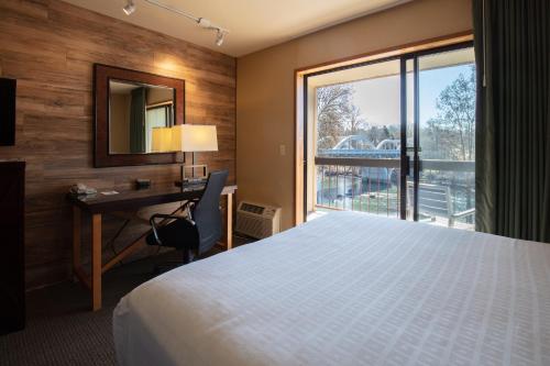 Habitación de hotel con cama, escritorio y ventana en Riverside Inn, en Grants Pass