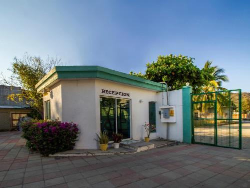 a small white building with a green door at Hotel Parotas Manzanillo in Manzanillo