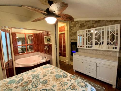 a bedroom with a bed and a tub and a ceiling fan at The Gables Inn in Hot Springs
