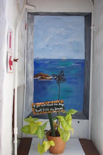 a window with a painting of the ocean and a potted plant at Aqua Marine Guest House in Port Elizabeth