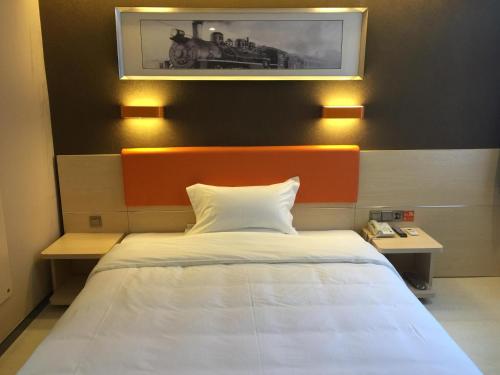 a bed in a room with a train picture on the wall at 7Days Premium Dalian Development Zone Wucaicheng rail station in Dalian
