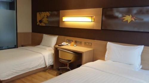 een hotelkamer met 2 bedden en een bureau met een telefoon bij 7Days Inn Zhangjiakou Chongli Yuxing Road in Zhangjiakou