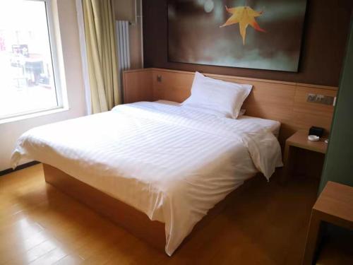 Un dormitorio con una cama blanca con una estrella en la pared en 7Days Inn Zhangjiakou Chongli Yuxing Road en Zhangjiakou