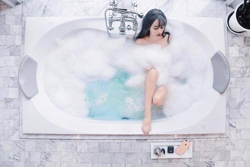Una donna seduta in una vasca da bagno piena di fumo di Hotel Once Bangkok a Bangkok