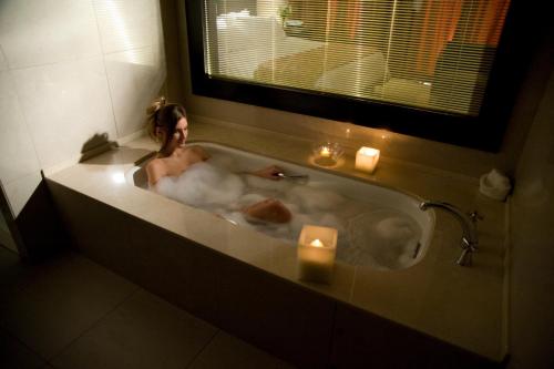 Una mujer está en una bañera con velas en Hotel Casino Magic en Neuquén