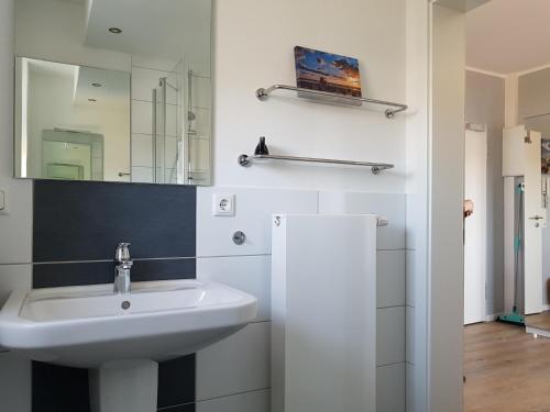 La salle de bains est pourvue d'un lavabo et d'un miroir. dans l'établissement Spuren im Sand, à Sankt Peter-Ording
