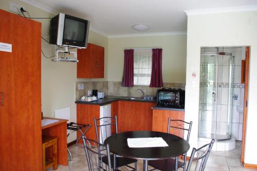 a kitchen with a table and a tv on the wall at Aqua Marine Guest House in Port Elizabeth