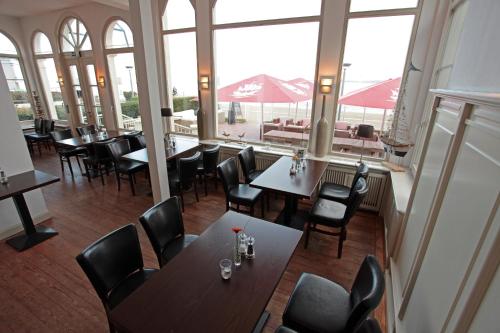 a restaurant with tables and chairs and large windows at Lieblingsplatz Hotel Strandperle in Travemünde