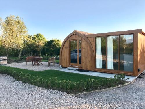 a small wooden cabin with a table and a picnic table at Orchard Glamping in Catterall