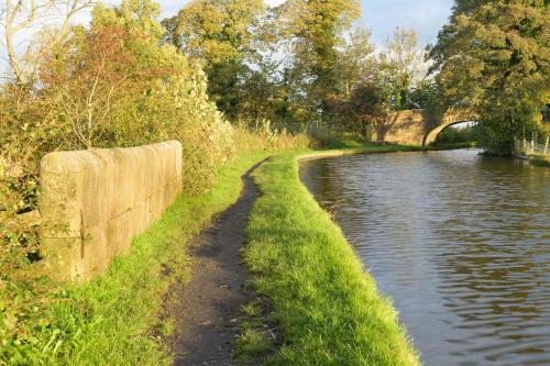 a path next to a river with a bridge at Orchard Glamping in Catterall
