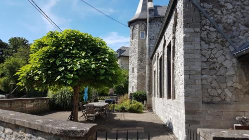 a tree next to a building with a table and a tree at L'Ecole in Dinant