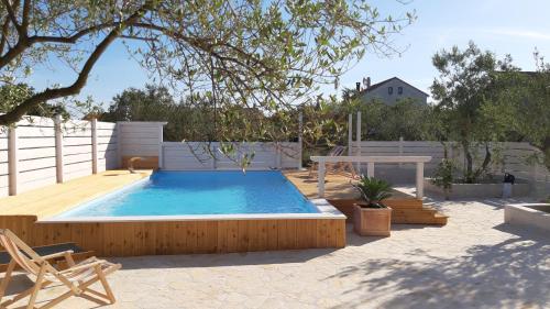 a swimming pool with a wooden deck and a table at Villa Nina in Biograd na Moru