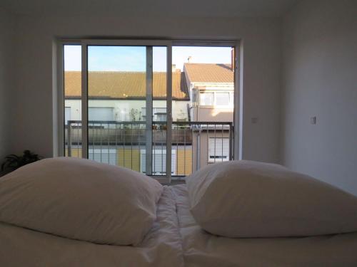 Bett mit zwei Kissen vor dem Fenster in der Unterkunft L8 Street - Q2 16 in Mannheim