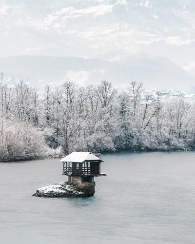a small house on an island in the water at Perucac Apartment in Perućac