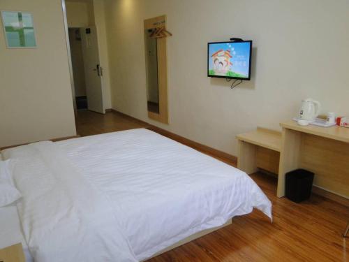sypialnia z białym łóżkiem i telewizorem z płaskim ekranem w obiekcie 7Days Inn Taihe Guoxing Auto and Agricultural Machine City w Ji'an