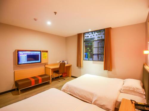 een hotelkamer met een bed, een bureau en een televisie bij 7Days Premium Zhangjiajie Railway Station Square in Zhangjiajie
