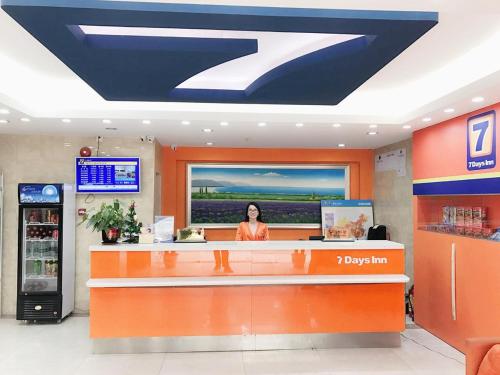 a woman standing at a cash counter in a store at 7Days Inn Shenzhen Sha Mei Metro Station in Shenzhen