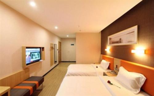 a hotel room with two beds and a flat screen tv at 7 Days Premium Dalian Zhuanghe Huanghai Avenue in Zhuanghe