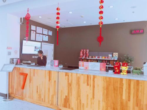 a woman sitting at a counter in a restaurant at 7Days Premium Dalian Airport in Dalian