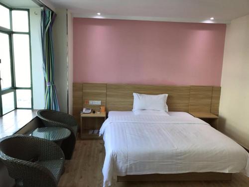 a bedroom with a large bed and two chairs at 7Days Inn Shenzhen Sha Mei Metro Station in Shenzhen