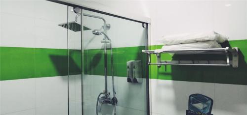 La salle de bains est pourvue d'une douche et d'un mur vert. dans l'établissement 7Days Inn Tangshan Silicon Valley Digital City, à Tangshan