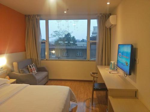 a hotel room with a bed and a desk with a television at 7Days Inn Emeishan Center in Leshan