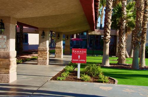 a sign in front of a building with palm trees at Ramada by Wyndham Yuma in Yuma