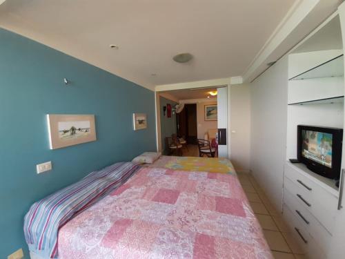 1 dormitorio con 1 cama y TV. en Atlántico Flat, en Natal