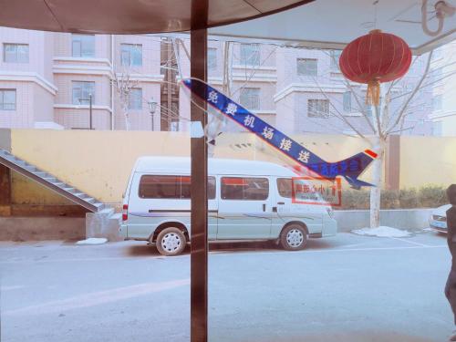 a white van is parked in a parking lot at 7Days Premium Dalian Airport in Dalian