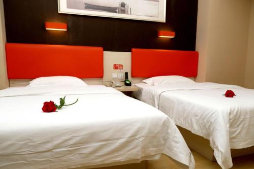 two beds in a hotel room with red headboards at 7Days Premium Dalian Airport in Dalian